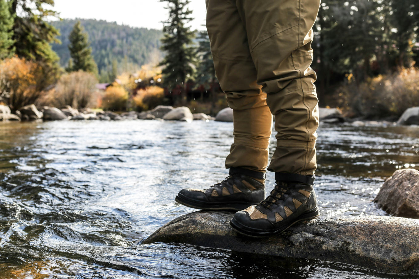 Hiker in water-resistant boots standing on a rock in a river
